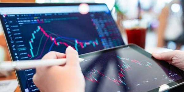 Person using a tablet and viewing financial trend graphs.